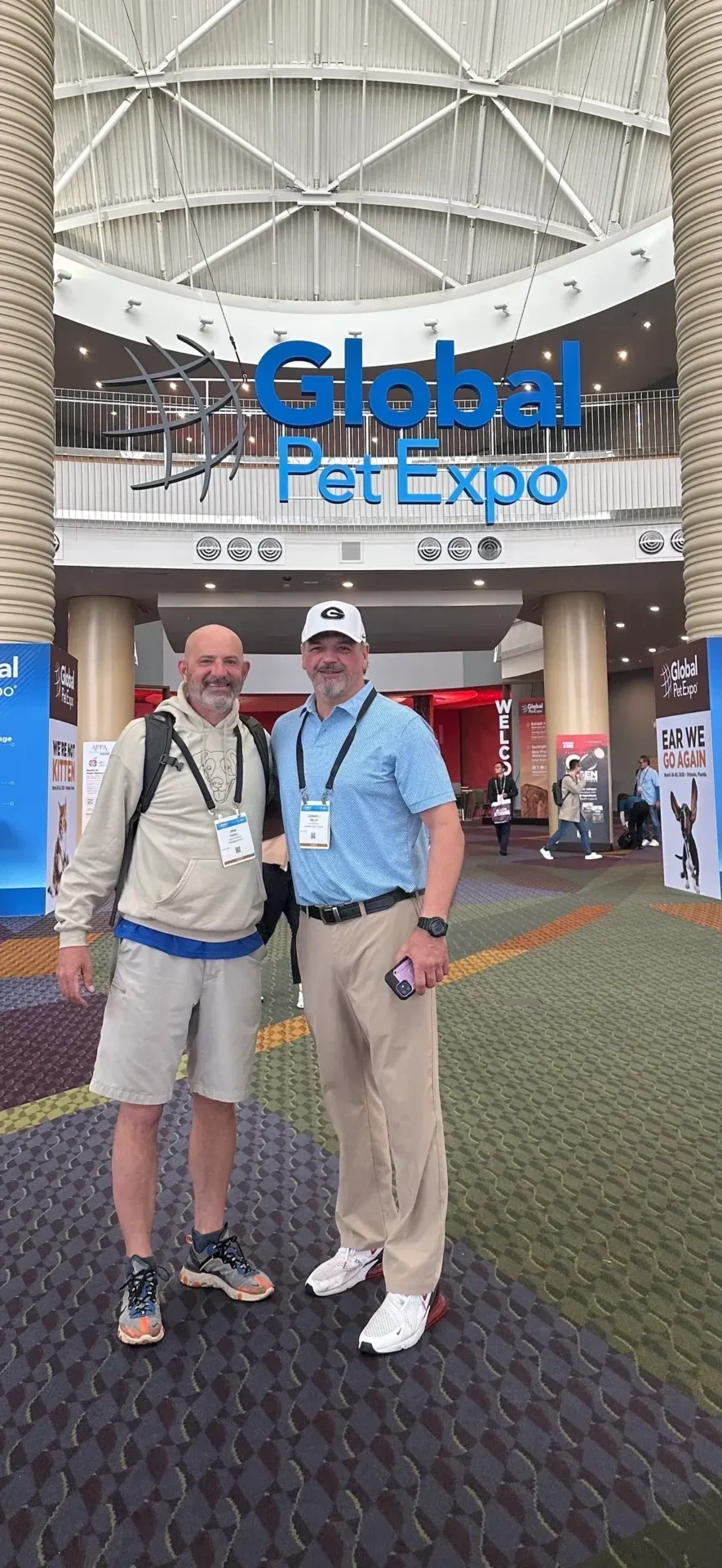 Two men standing in front of a building with the words " pet expo ".